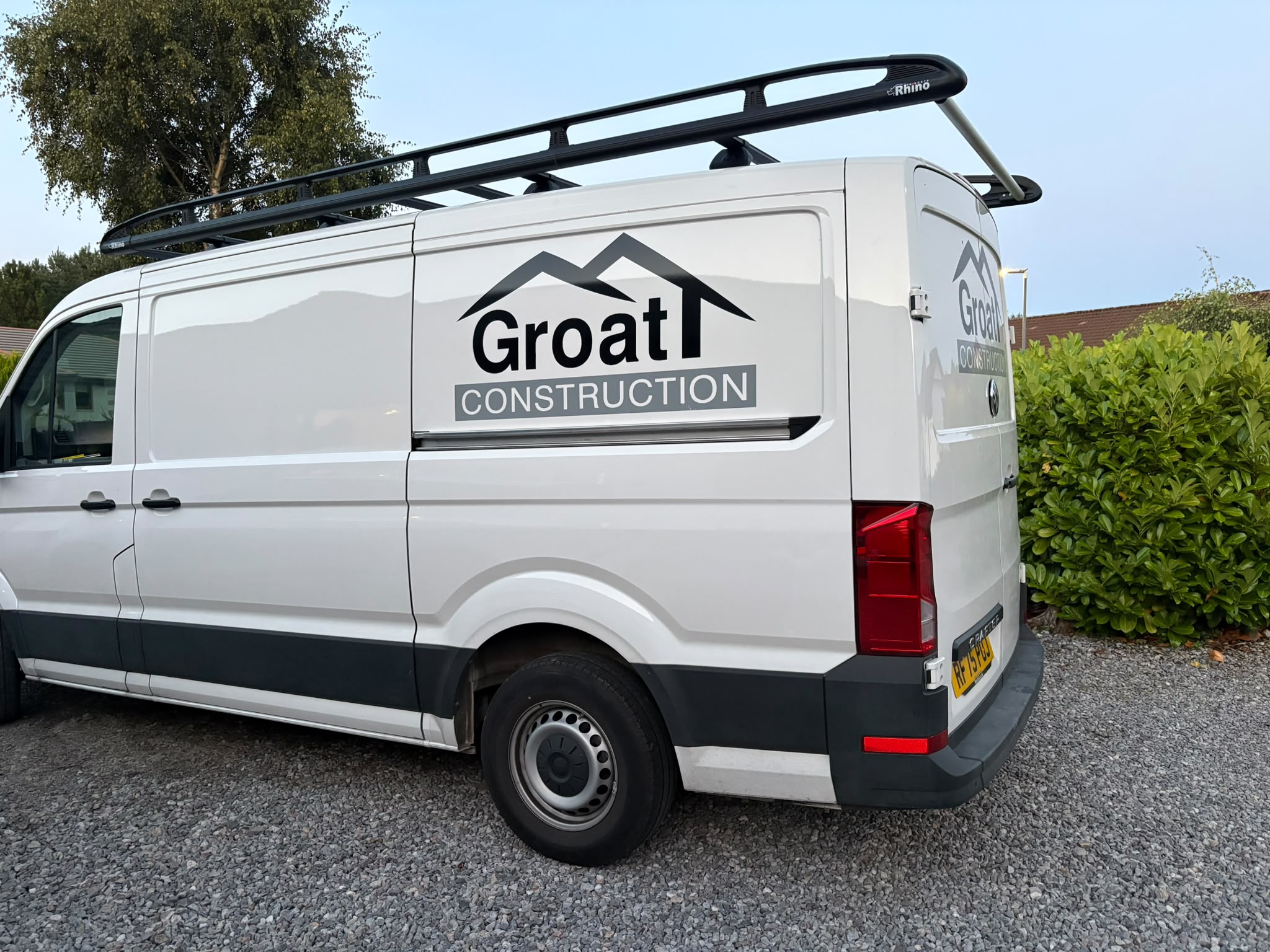 The sign-written Groat Construction van, fitted with a roof rack, parked on a driveway.