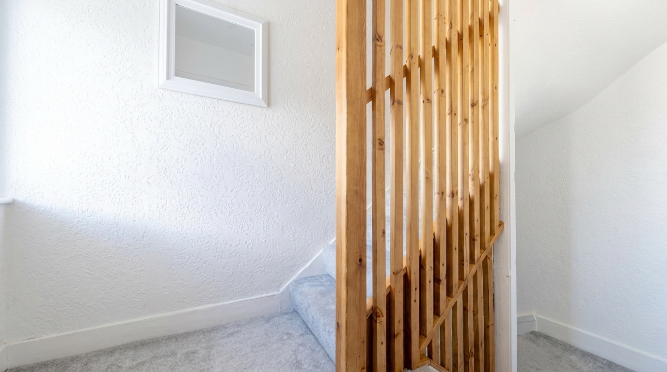 A refurbished interior with a timber slat screen dividing the room and freshly plastered walls, by Groat Construction.